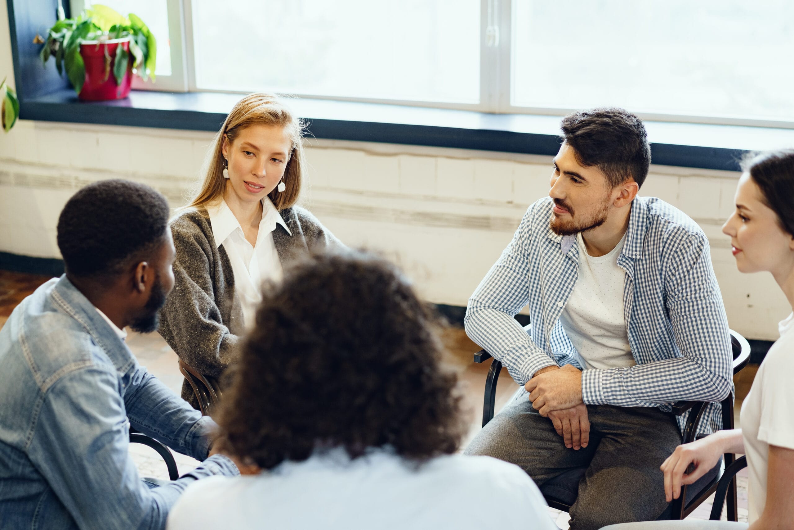 A group of people sitting in a circle with a man in the middle.